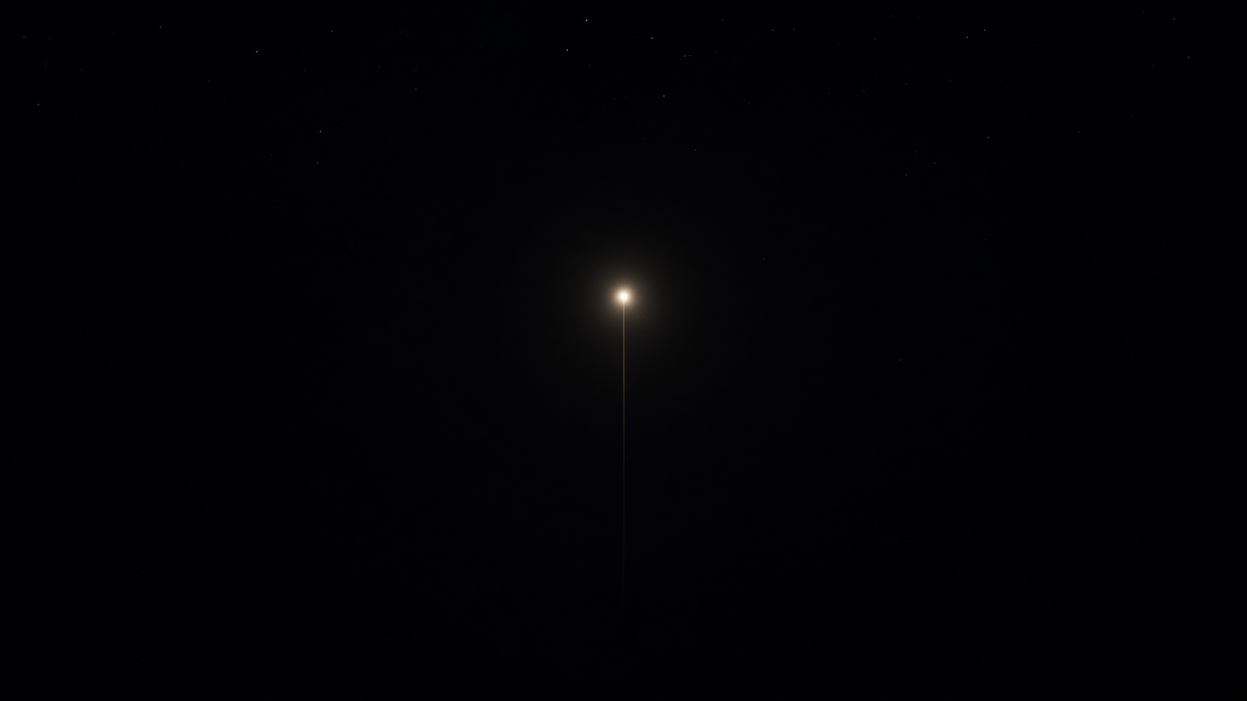 A single warm point of light in a wide dark, a faint gold thread falling through the night.